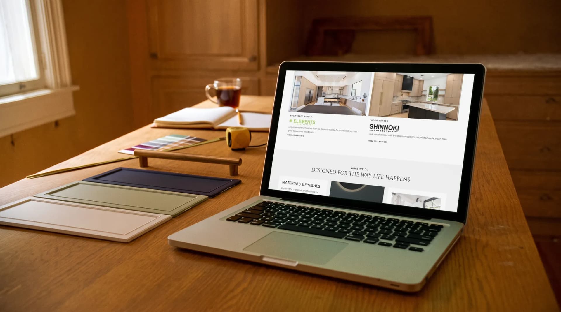 The Dreamline Cabinetry collections page on a laptop beside cabinet-door samples in a kitchen before its remodel