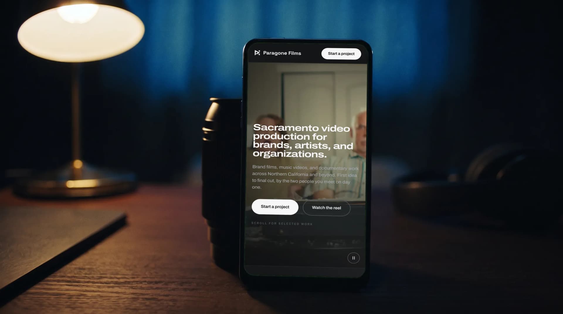 The Paragone Films website on a phone on an edit-room desk beside a cinema lens