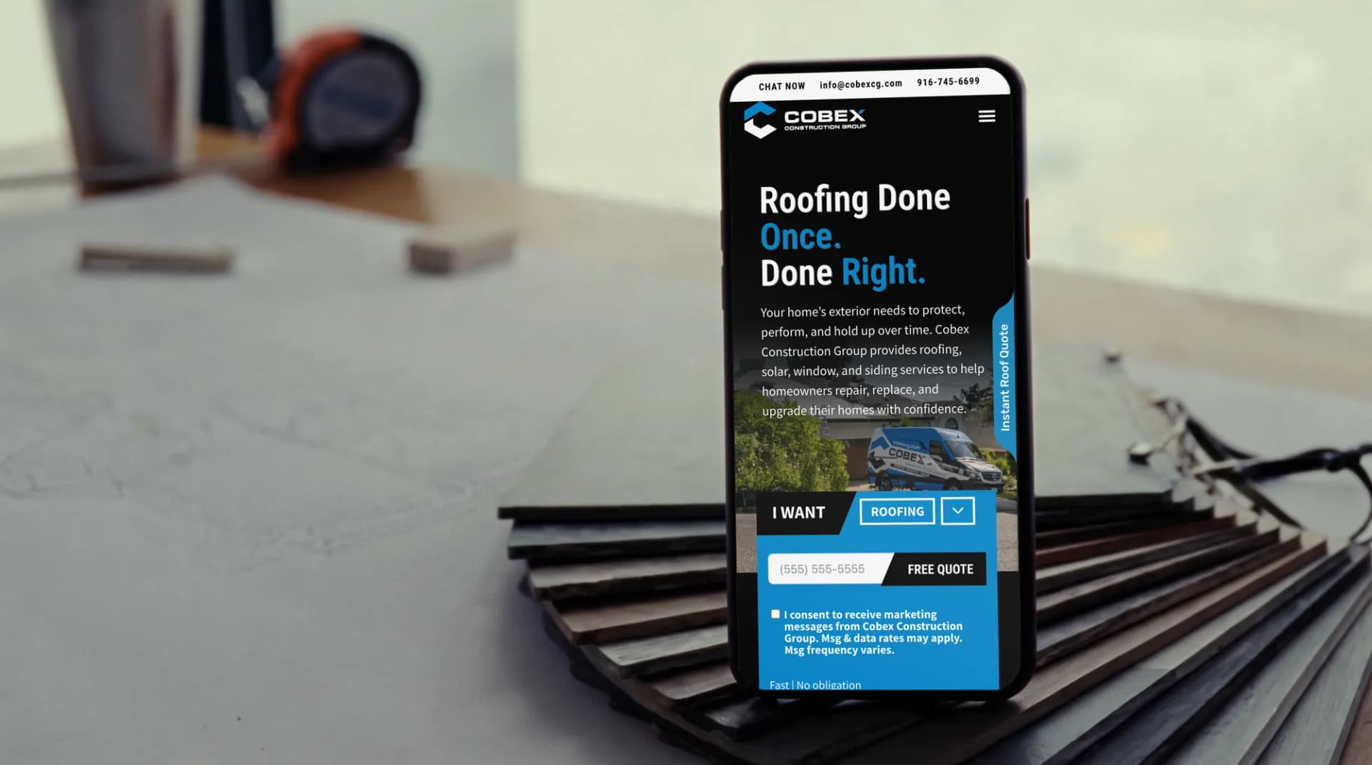 The Cobex Construction Group website on a phone on an estimating table beside asphalt shingle samples